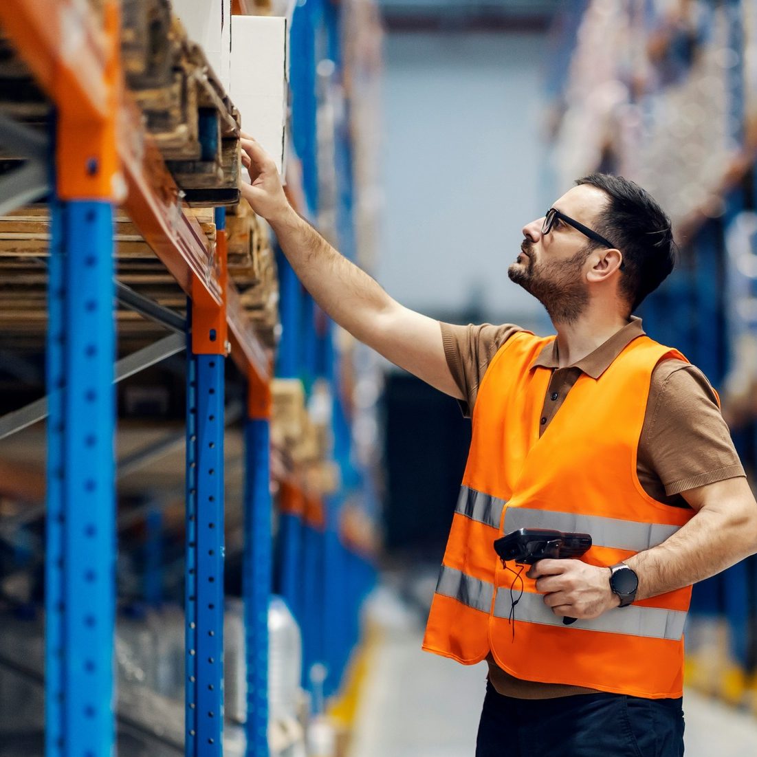 Warehouse associate scanning inventory beside storage racks